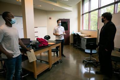 Dr. Cale Stolle presents scholarships to senior engineering students Ryan Lasauskas, left, and Kenny Kemp, right. They are standing in a classroom in the Lied Science and Mathematicsbuilding. 